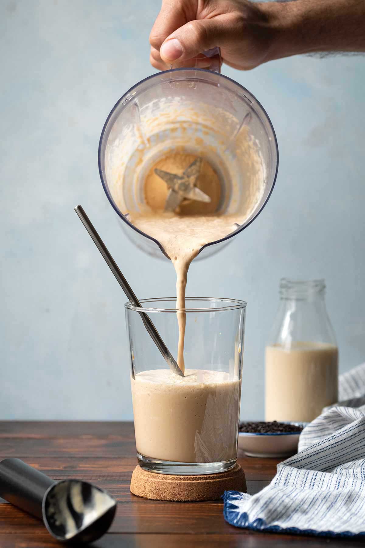 Pouring coffee ice cream frappe into the glass from a blender.