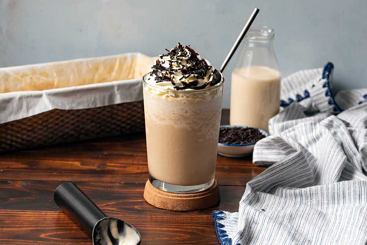 Coffee ice cream frappe served in a tall glass with chocolate syrup and sprinkles.