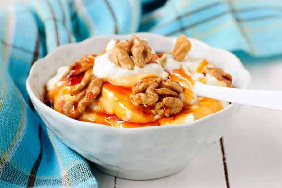 Greek yogurt with honey and walnuts inside a bowl.