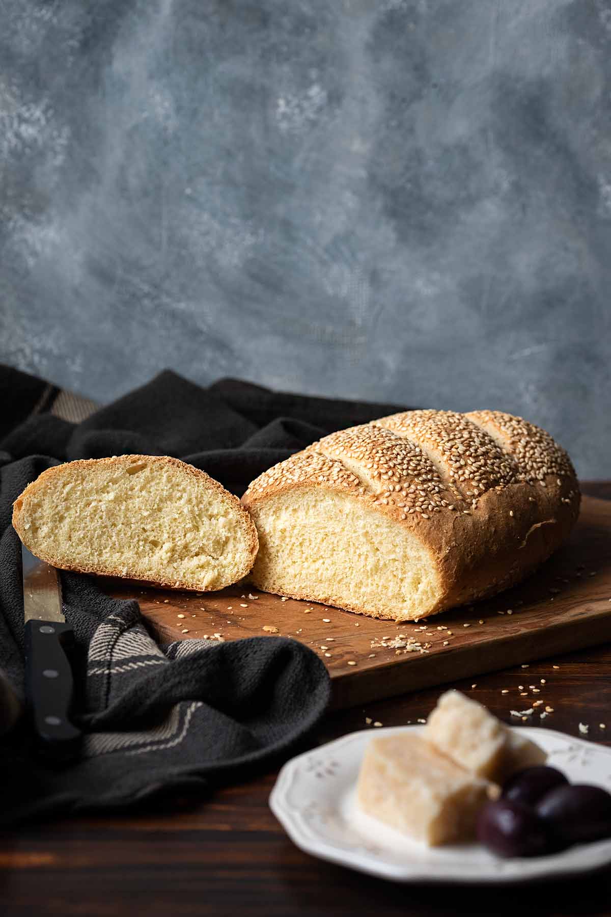 Greek village bread, sliced on a cutting board, served with olives.