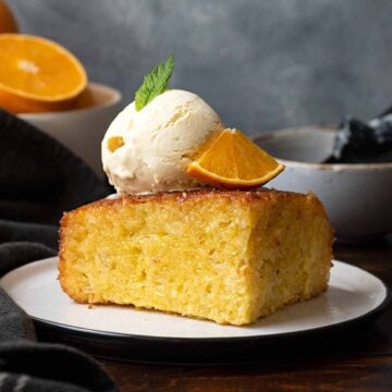 A slice of A slice of Portokalopita with a scoop of vanilla ice cream.