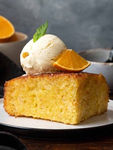A slice of A slice of Portokalopita with a scoop of vanilla ice cream.