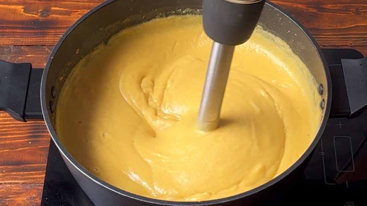 Blending the finished fava with an immersion blender.