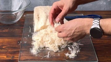 Two hands fluffing up the kataifi strands.