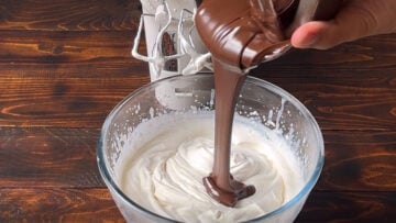 Adding melted dark chocolate to whipped cream.