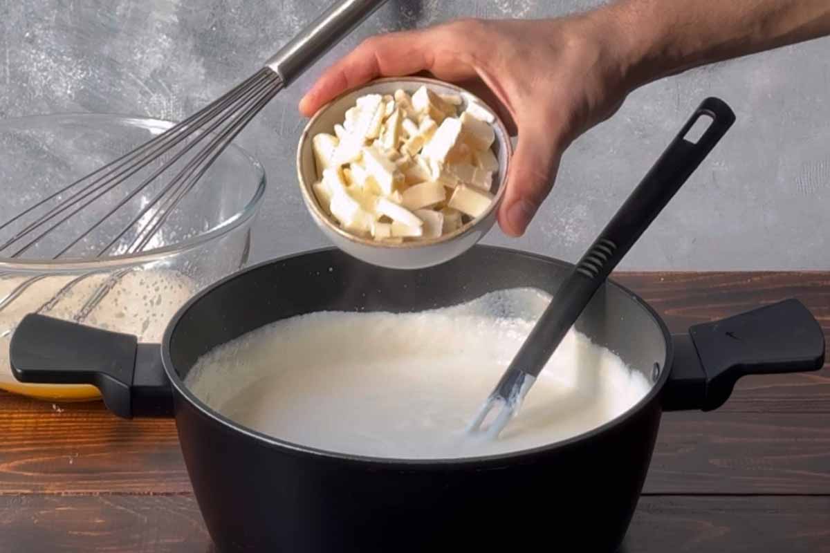A hand adding white chocolate to semolina custard.