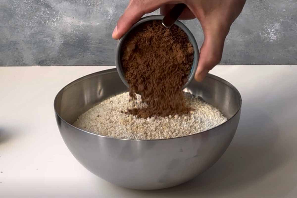 A hand adding brown sugar to ground walnut mixture.