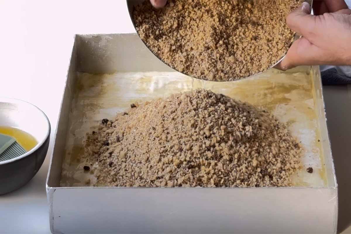 Adding the nut mixture over the bottom layers of phyllo.