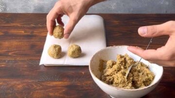 A hand forming balls with the pistachio white chocolate filling.