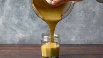 Pouring pistachio butter into a glass jar.