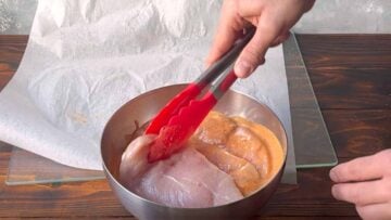 Chicken breasts inside a bowl with Greek yogurt marinade.