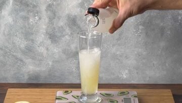 A hand adding sparkling lemonade to the glass.