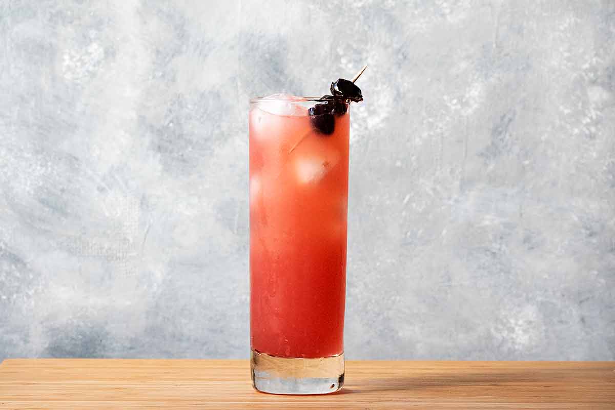 A glass with ouzo, lime and tart cherry juice.