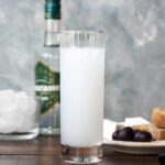 A tall narrow glass filled with ouzo and water.