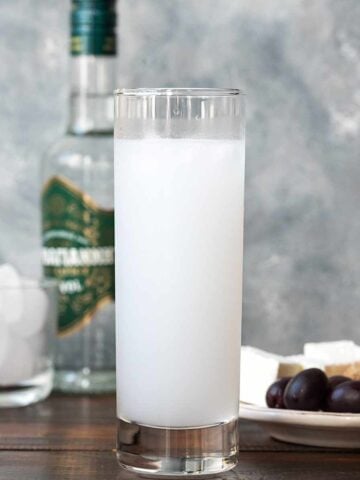 A tall narrow glass filled with ouzo and water.