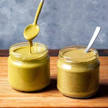 Two jars with pistachio butter made with peeled and unpeeled nuts.
