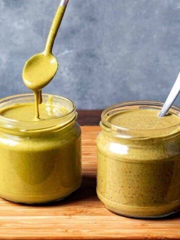 Two jars with pistachio butter made with peeled and unpeeled nuts.
