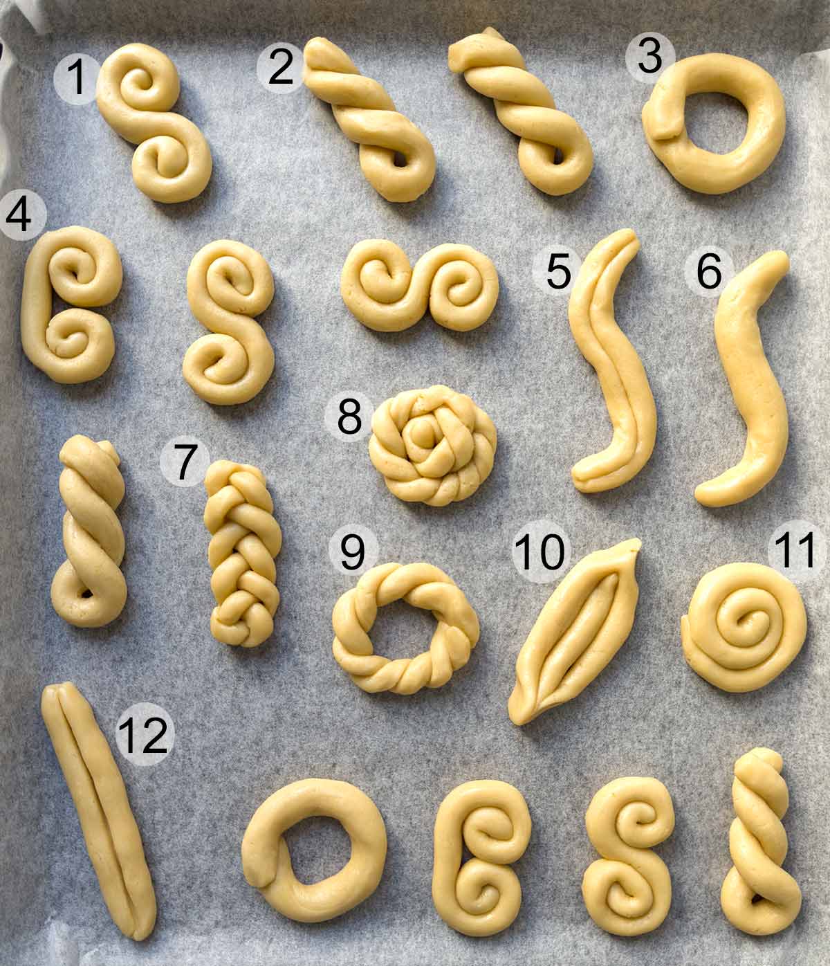 Greek koulourakia on a baking sheet with 12 different shapes.