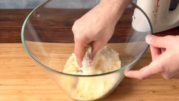 A hand rubbing the orange zest with the sugar.