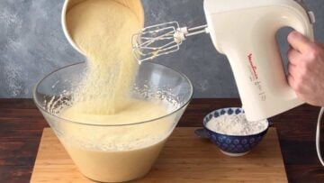 A hand adding semolina to the egg mixture.
