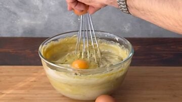 Two hands adding a egg to the filling.