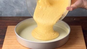 Cake batter being poured in a metal pan.
