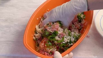 Two hands mixing the filling for dolma.