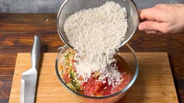 Adding rice to a bowl with grated vegetables.