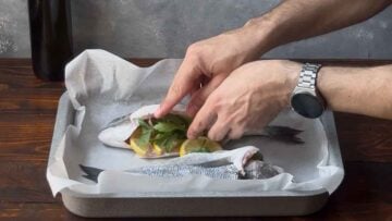 Stuffing the fish with lemon slices.