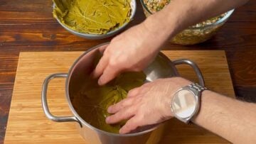Grape leaves layered on the bottom of a pot.
