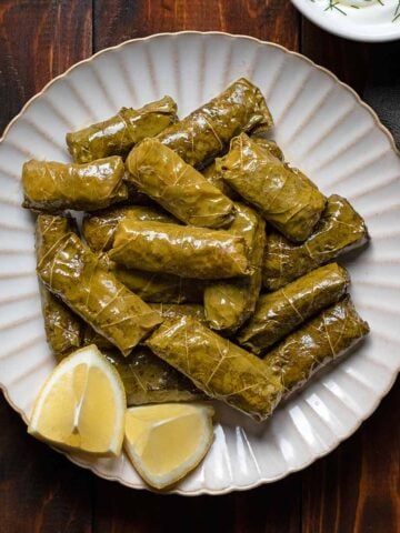 Dolmades, Greek stuffed grape leaves with rive on a plate. Featured.