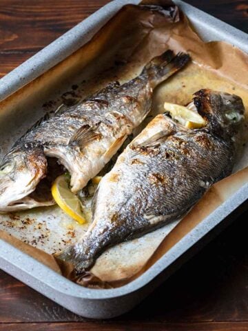 Two sea bream fish on a baking pan.