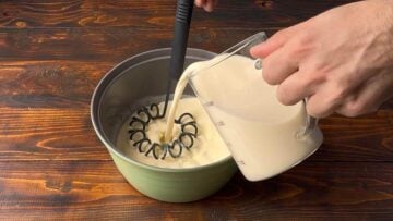 Adding milk to a pot with semolina.