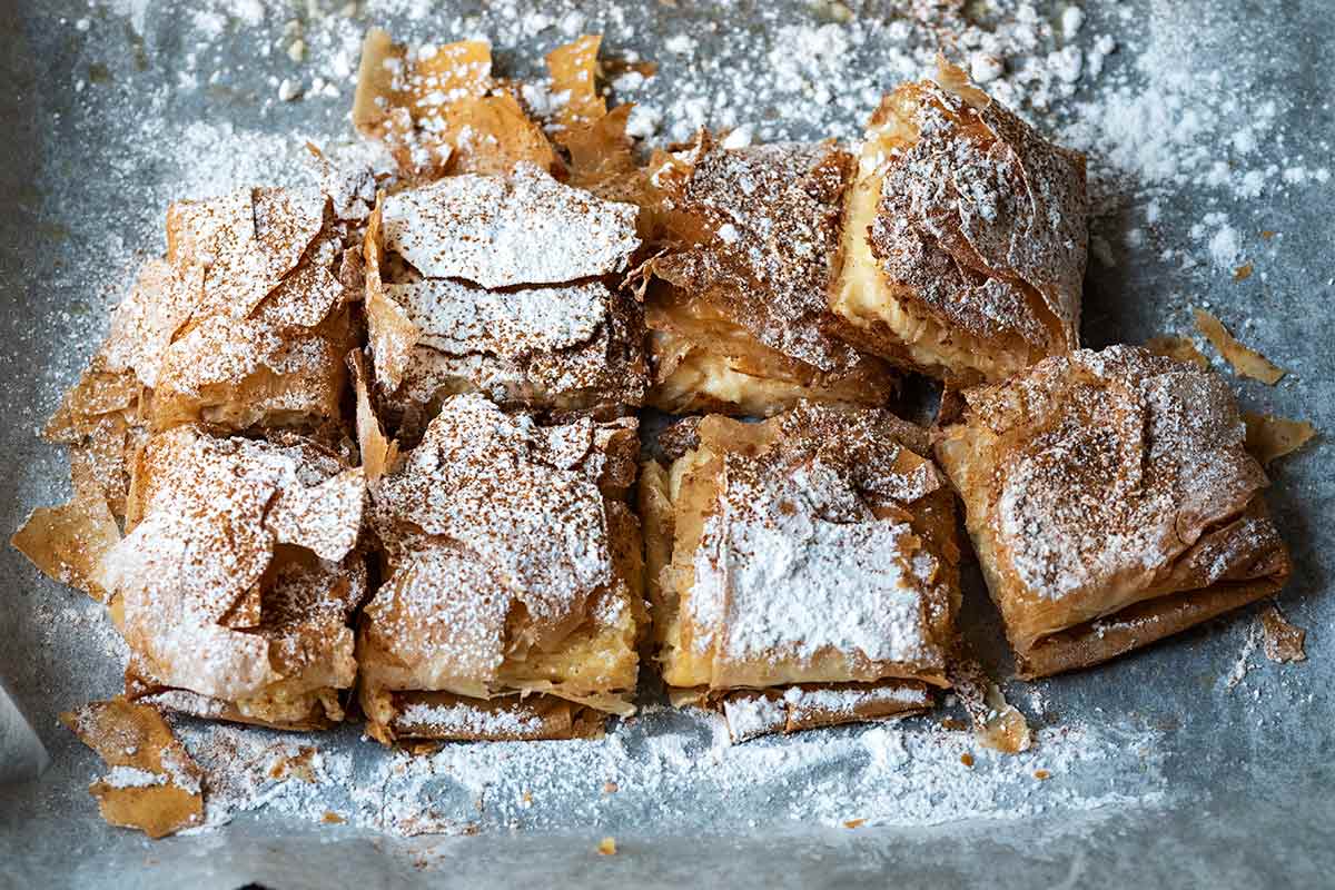 Greek custard pie with phyllo pastry, sprinkled with icing sugar and cinnamon.