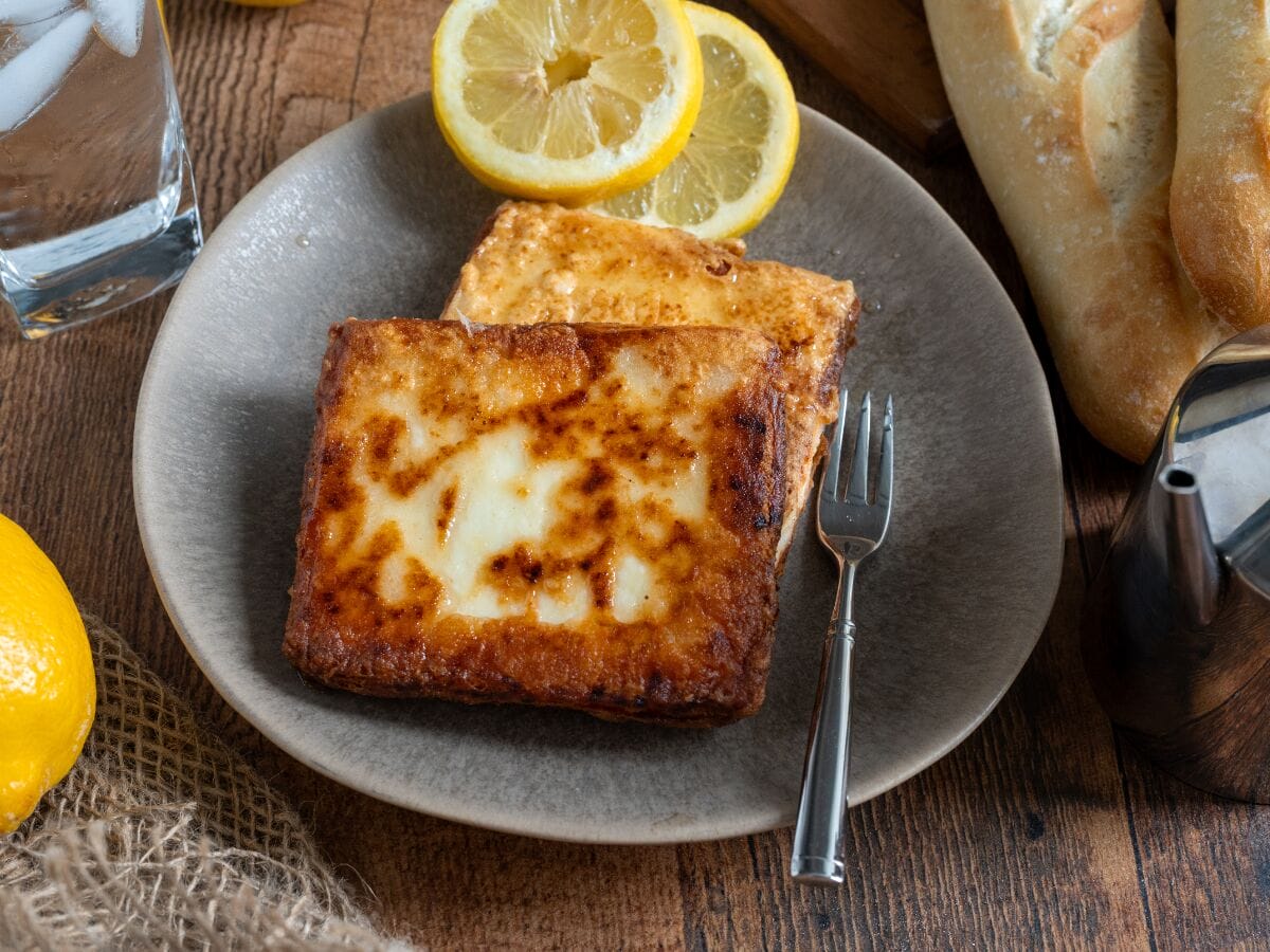 Fried pieces of cheese on a plate and lemon slices.