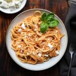 A plate with tomato pasta and feta.