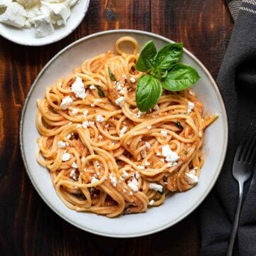 A plate with tomato pasta and feta.