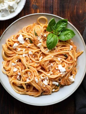 A plate with tomato pasta and feta.