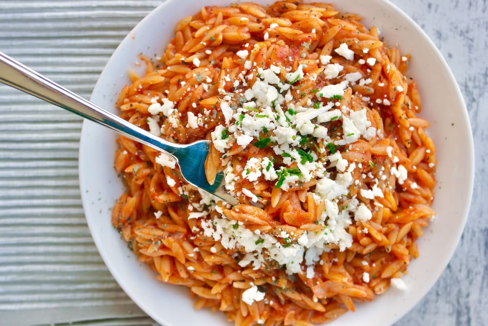 Greek orzo with tomato and feta served on a plate.