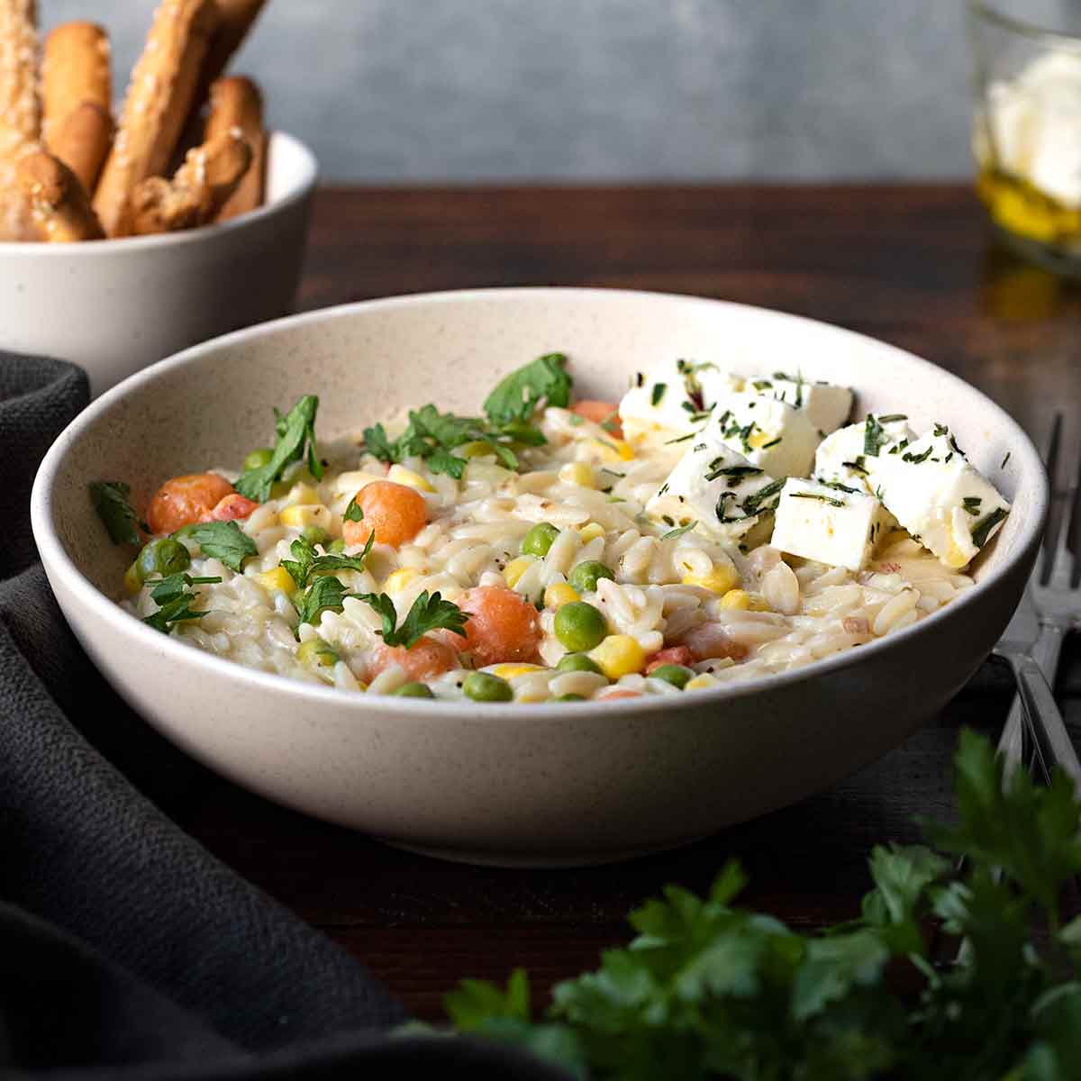 Creamy orzo pasta with vegetables and feta cheese in a bowl.
