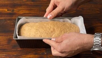 A risen barley loaf inside a loaf pan.