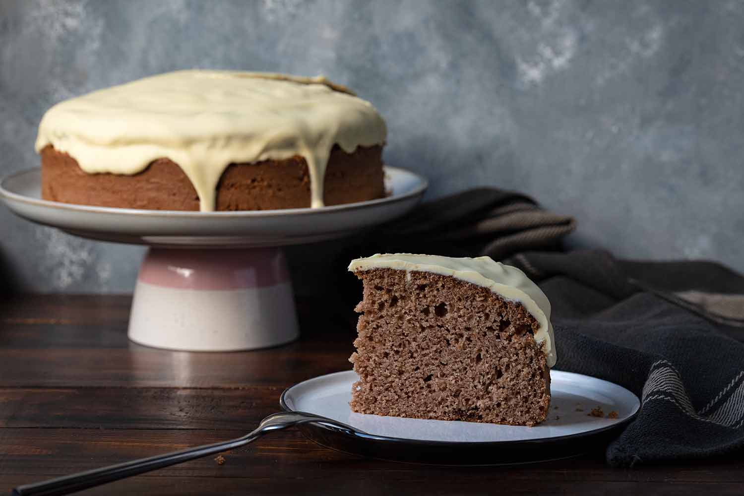 Healthy date cake on a cake stand and a slice on a plate.