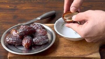 Two hands removing the pit from a date.