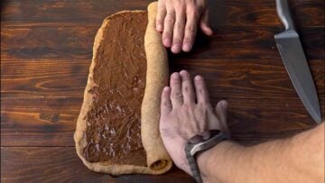 Two hands rolling the dough into a log.