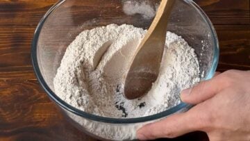 A bowl with barley flour and a wooden spoon.