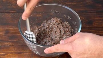 A hand mixes flaxseed and chia seeds in a bowl.