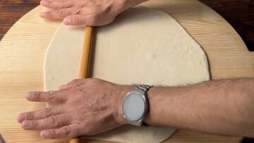 Two hands rolling the dough into a sheet.
