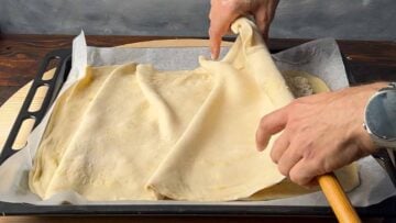 Two hands covering the piw with the second sheet of phyllo.
