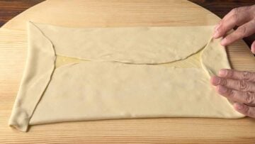 Two hands folding the phyllo.