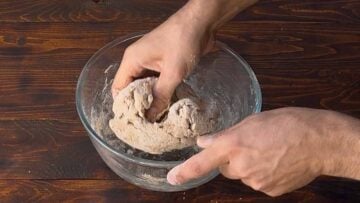 A hand kneading pizza dough.